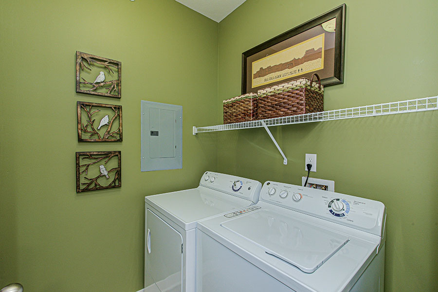 Laundry room with washer, dryer, and storage baskets on wire shelf.