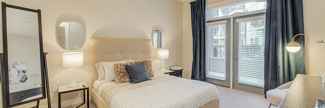 Master bedroom with several bright light fixtures located at Penrose on Mass Apartments.